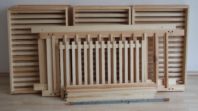 Alle Teile unseres 10er-Holzregals. 10 Schubladen, 2 Seitenteile, 4 Querstreben ein Deckelgitter sowie 4 Gewindestangen mit 8 Muttern zum Befestigen. Beim 15er sind es 5 weitere Schubladen und längere Seitenteile.